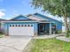 Charming blue single-story home with a well-manicured lawn and a white two-car garage at 1515 Oak Hill Trl, Kissimmee, FL 34747