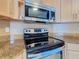 Close up on modern oven and cooktop, with granite countertops and stainless steel microwave above at 1515 Oak Hill Trl, Kissimmee, FL 34747