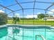 The tranquil pool is enclosed by a screen and situated against a backdrop of trees and landscaping at 1515 Oak Hill Trl, Kissimmee, FL 34747