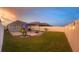Beautiful backyard at dusk, complete with a pergola, string lights, a fire pit, and well-manicured landscaping at 1940 Egret Meadows Ave, Kissimmee, FL 34744