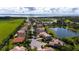 Aerial view of a community next to a lake with homes having tile roofs and well-maintained lawns at 1950 Windward Oaks Ct, Kissimmee, FL 34746