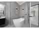 Bathroom featuring tiled walls, modern soaking tub, dark fixtures, and decorative lighting at 1950 Windward Oaks Ct, Kissimmee, FL 34746