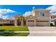 Charming two-story home featuring a tile roof, well-manicured lawn, palm trees, and a brick driveway leading to a two-car garage at 1950 Windward Oaks Ct, Kissimmee, FL 34746