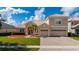 Charming two-story home featuring a tile roof, well-manicured lawn, palm trees, and a brick driveway leading to a two-car garage at 1950 Windward Oaks Ct, Kissimmee, FL 34746
