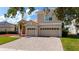 View of the attached two-car garage and brick driveway showcasing the home's exterior and landscaping at 1950 Windward Oaks Ct, Kissimmee, FL 34746