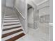 Staircase with white risers and wood treads next to open hallway with marble floors and wainscotting at 1950 Windward Oaks Ct, Kissimmee, FL 34746