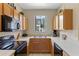 Efficient kitchen featuring wood cabinets, black appliances, and a double sink for easy cleanup at 2708 Camaro Dr, Kissimmee, FL 34746