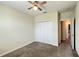 Neutral bedroom showcasing a ceiling fan and carpeted floor, with closet and hallway access at 4634 Tribute Trl, Kissimmee, FL 34746