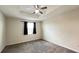 This carpeted bedroom has a ceiling fan and a window with dark curtains at 4634 Tribute Trl, Kissimmee, FL 34746