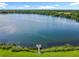 Stunning aerial shot of a lake with a wooden dock, surrounded by lush greenery and open skies at 5312 Kingswood Dr, Orlando, FL 32810