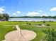 Scenic lake view featuring a circular patio surrounded by green grass, offering a peaceful retreat in a community setting at 5312 Kingswood Dr, Orlando, FL 32810