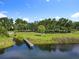 Lakeside view showcasing a wooden dock on the water and lush green areas with mature trees in a serene community setting at 5312 Kingswood Dr, Orlando, FL 32810