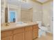 Bright bathroom features a sink with wood cabinets, a large mirror, and a toilet at 651 Regina Cir, Oakland, FL 34787