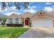 Inviting home with a red front door, lush landscaping, and a well-maintained lawn at 651 Regina Cir, Oakland, FL 34787