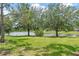 Picturesque backyard featuring a tranquil pond framed by mature trees and lush green grass at 6808 Goldflower Ave, Harmony, FL 34773