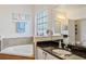Bright bathroom with a garden tub, tile accents, and granite countertops at 6808 Goldflower Ave, Harmony, FL 34773