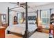 Bedroom with a four poster bed, dark trim, and large windows at 6808 Goldflower Ave, Harmony, FL 34773