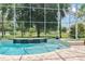 Screened pool with a charming waterfall feature and built-in spa, set against a backdrop of lush greenery at 6808 Goldflower Ave, Harmony, FL 34773