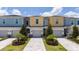 Street view featuring colorful townhouses with one-car garages and manicured landscaping, offering a visually appealing community setting at 7920 Draw St, Reunion, FL 34747