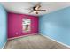 Bright bedroom with vibrant blue and pink walls, neutral carpeting, and a ceiling fan at 8 Orchid Ct, Kissimmee, FL 34759