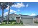 Charming home with a two-car garage, manicured landscaping, and beautiful palm trees against a bright blue sky at 10722 Clover Walk Dr, Orlando, FL 32825