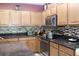 Well-lit kitchen features dark countertops, wooden cabinets, and stainless steel appliances at 10722 Clover Walk Dr, Orlando, FL 32825