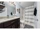 A clean bathroom features a shower/tub combination, dark cabinets, a granite countertop, and stylish decor at 13129 Cog Hill Way, Orlando, FL 32828