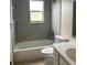 Modern bathroom with gray tiled walls, tub, toilet and sink at 15 Clear Way, Ocala, FL 34472