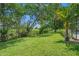 Lush backyard featuring a well-maintained lawn, mature trees, and a secure fence at 1525 Gants Cir, Kissimmee, FL 34744