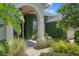 Charming front entrance with lush greenery, a covered archway, and manicured landscaping at 1525 Gants Cir, Kissimmee, FL 34744