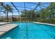 Large pool with a screened enclosure, set against a backdrop of swaying palm trees and manicured landscaping at 1525 Gants Cir, Kissimmee, FL 34744