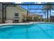 Beautiful pool area showcasing an outdoor kitchen and seating beneath a screened enclosure at 1525 Gants Cir, Kissimmee, FL 34744