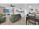 Open-concept living room featuring neutral tile floors, comfortable green sofas, and a large flat-screen TV at 1710 Thor Ave, Apopka, FL 32703