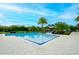 Community pool with a beach entry, shaded seating, and views of surrounding trees and clubhouse in the background at 1855 Treasure Cv, Kissimmee, FL 34747