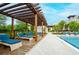 Comfortable lounge seating by the pool with a shaded pergola and views of the clubhouse and lush landscaping at 1855 Treasure Cv, Kissimmee, FL 34747