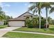 Inviting home showcasing a well-maintained lawn, mature palms, and an attached two-car garage at 2612 Keswick Ct, Kissimmee, FL 34744