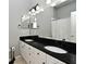 Bathroom featuring double sinks with white cabinets and black countertop and modern fixtures at 267 Goldenrain Dr # 30, Celebration, FL 34747