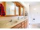 Bright bathroom featuring double sinks with wood cabinetry and a tiled shower with floral design at 2695 Hilliard Ct, Kissimmee, FL 34744