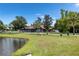 Exterior shot of a house on a lush green lawn with mature trees and pond, offering serene views and privacy at 2695 Hilliard Ct, Kissimmee, FL 34744