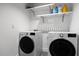 Bright laundry room featuring modern white front-load washer and dryer with floating shelves above at 3807 S Semoran Blvd, Orlando, FL 32822