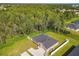 Overhead shot of single-Gathering home featuring an expansive yard and a backdrop of dense trees and a clear blue sky at 536 Bristol Cir, Kissimmee, FL 34758