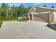 Wide driveway leading to a tan home with a 2-car garage, surrounded by green lawn and trees in the background at 536 Bristol Cir, Kissimmee, FL 34758