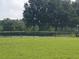 A tennis court surrounded by green grass and mature trees at 7110 Red Lantern Dr # 23, Harmony, FL 34773