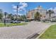 Inviting resort entrance featuring meticulously maintained landscaping, a circular driveway, and palm trees at 7458 Gathering Dr, Kissimmee, FL 34747
