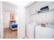 Laundry room with washer, dryer and storage next to a bedroom with hardwood floors at 8112 Princess Palm Ln, Kissimmee, FL 34747