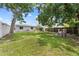 A sprawling backyard is framed by mature trees and a wooden fence, offering ample space for outdoor activities and privacy at 1501 Delaware Ave, St Cloud, FL 34769