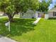 Well-manicured lawn and a large tree, enhancing the curb appeal of this charming home in a quiet neighborhood at 1501 Delaware Ave, St Cloud, FL 34769