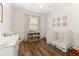 Bright Bedroom with a white crib, wood floors, and a window with light-filtering curtains at 2823 Sail Breeze Way, Kissimmee, FL 34744