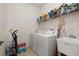 Laundry room with white washer and dryer, sink, tile floor and overhead storage shelf at 2823 Sail Breeze Way, Kissimmee, FL 34744
