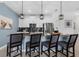 Chic kitchen featuring white cabinetry, a breakfast bar with seating, modern pendant lights, and stainless appliances at 4403 Scene Ln, Kissimmee, FL 34746